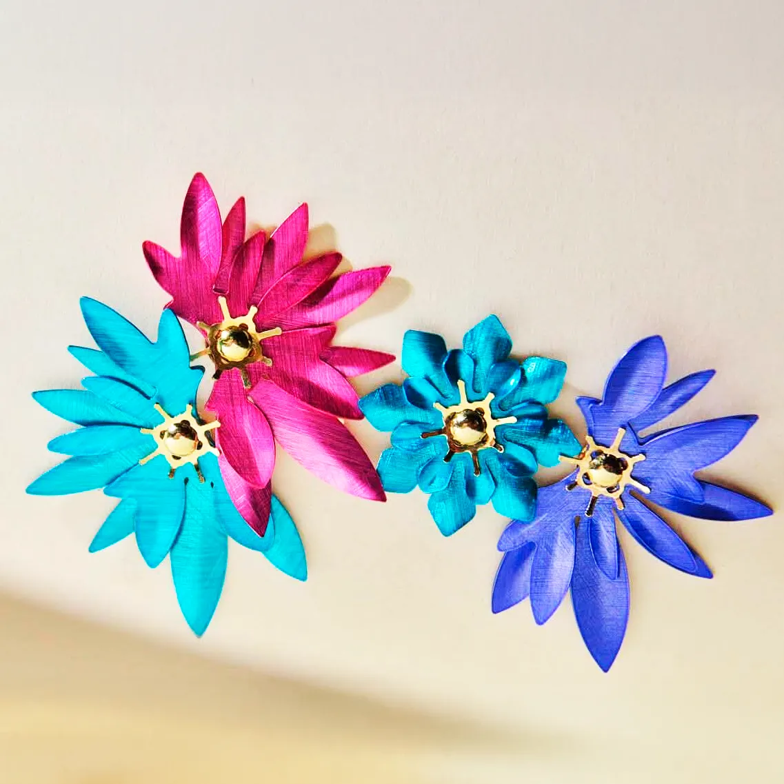 Pendientes con forma de flor en tonos fucsia, turquesa y azul eléctrico de Aeren Joyas.